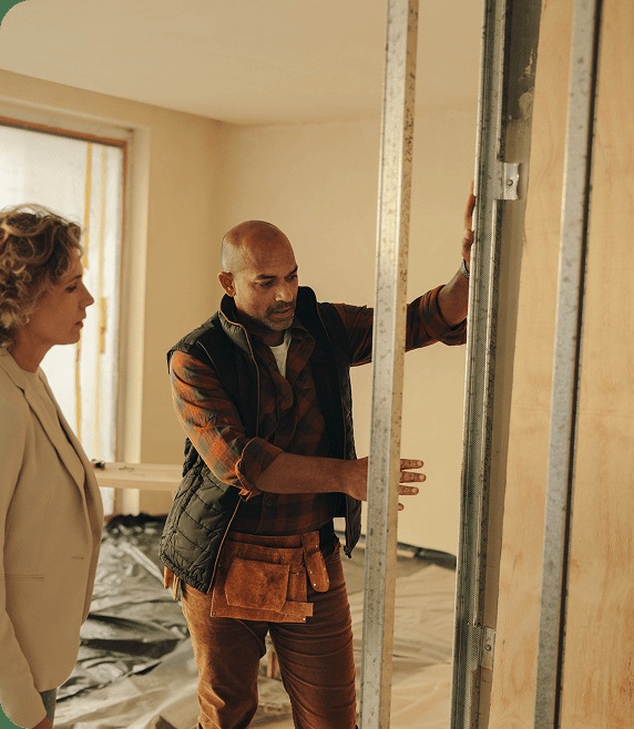 A contractor discussing an unfinished interior wall with a homeowner