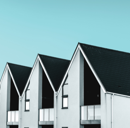 Row of modern modular homes with dark gabled roofs against a teal sky
