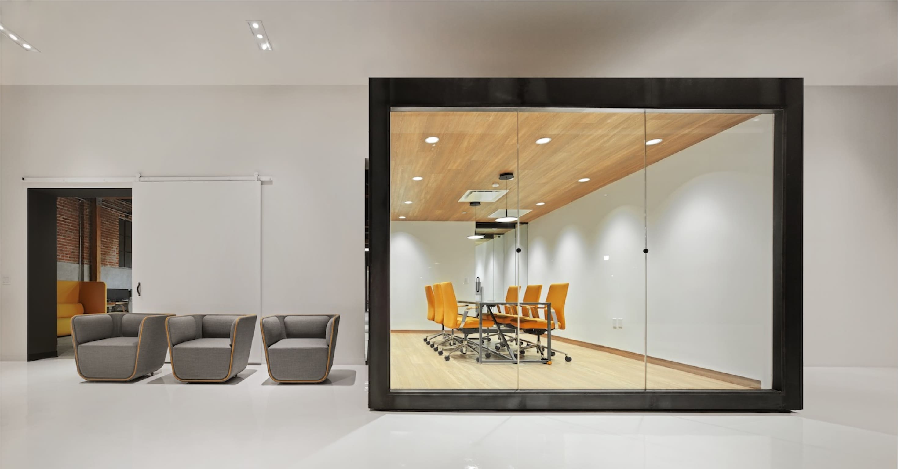 Supplyframe DesignLab interior with a glass-walled meeting room, yellow chairs and adjacent seating