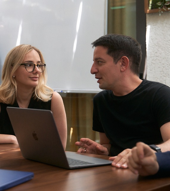 Two Surf team members discussing work beside a laptop