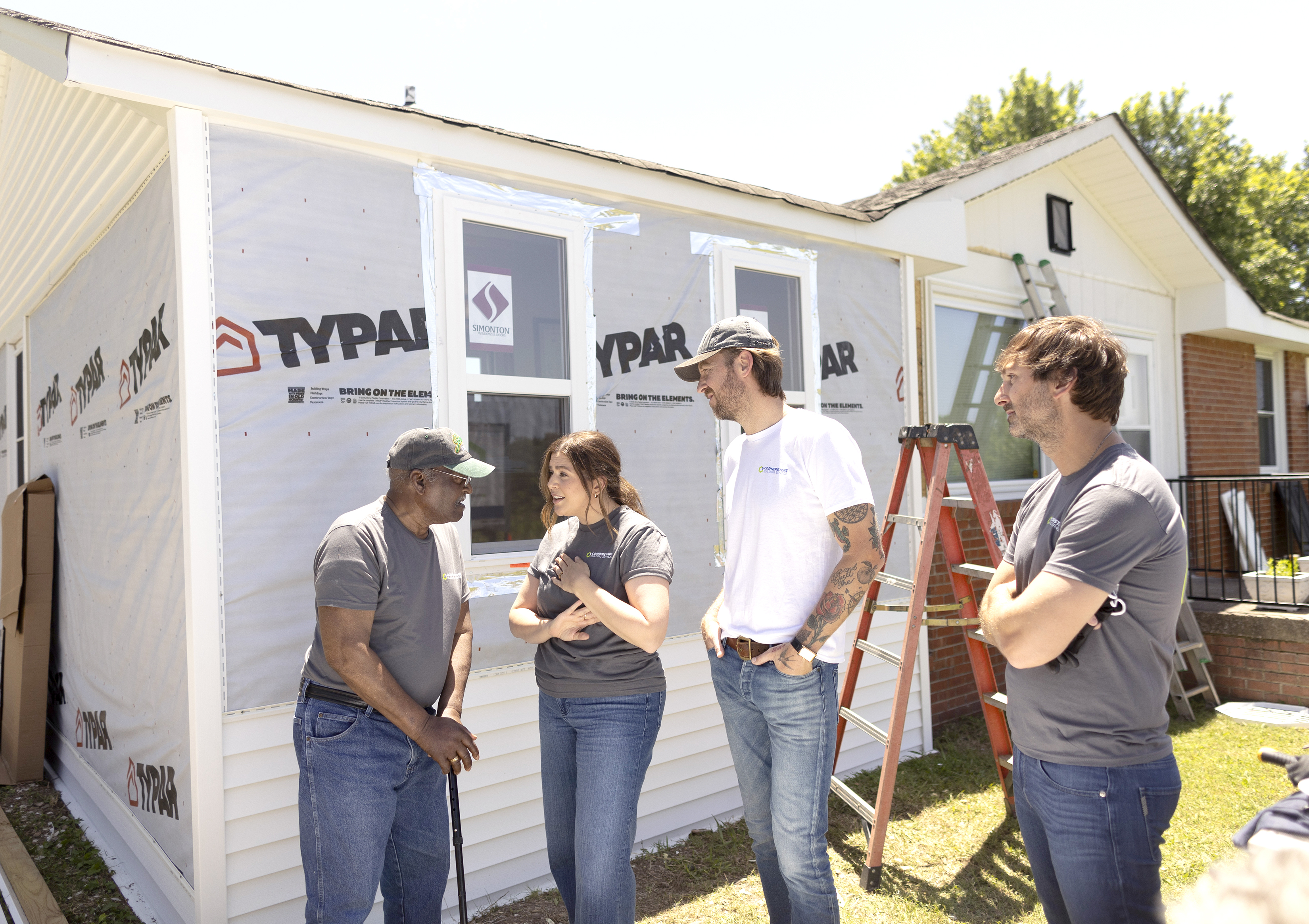Lady A members speak with homeowner James Mitchell beside a home under renovation in Murfreesboro, Tennessee