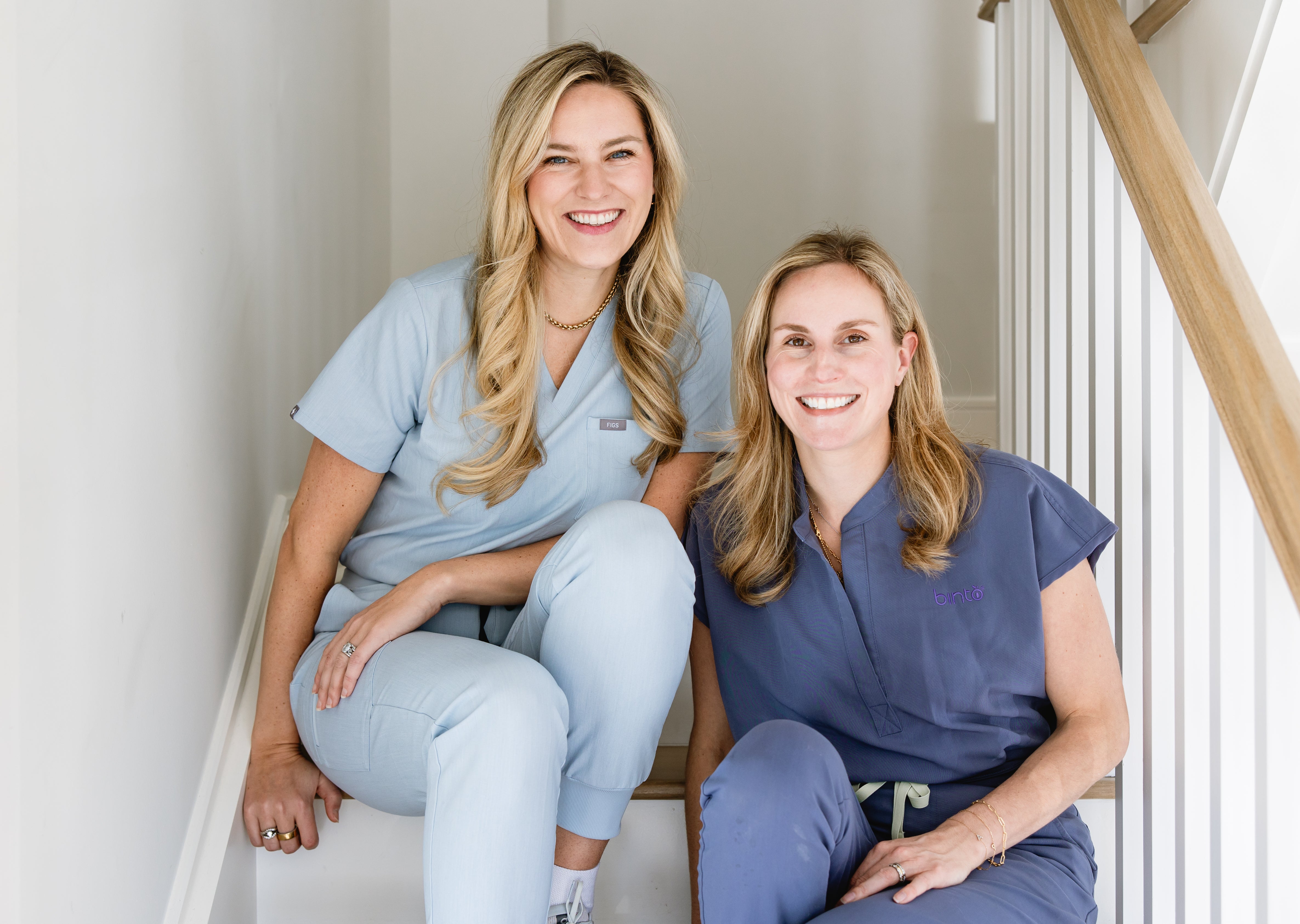 BINTO co-founders Andi Lucas Schmerin and Suzie Devine seated together in scrubs