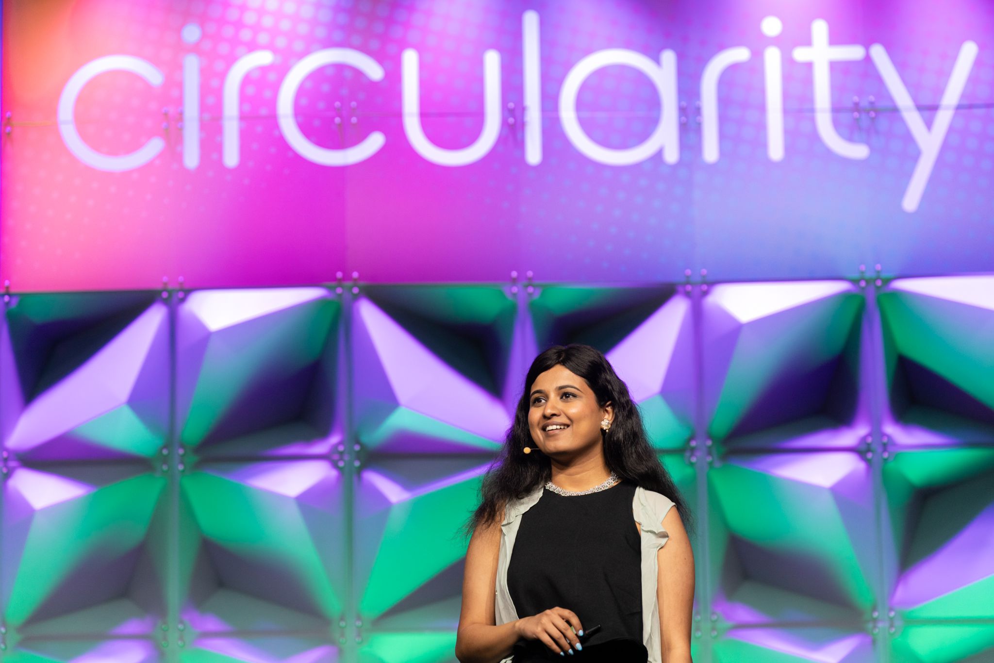 Svanika Balasubramanian speaking on a stage with a colorful Circularity backdrop