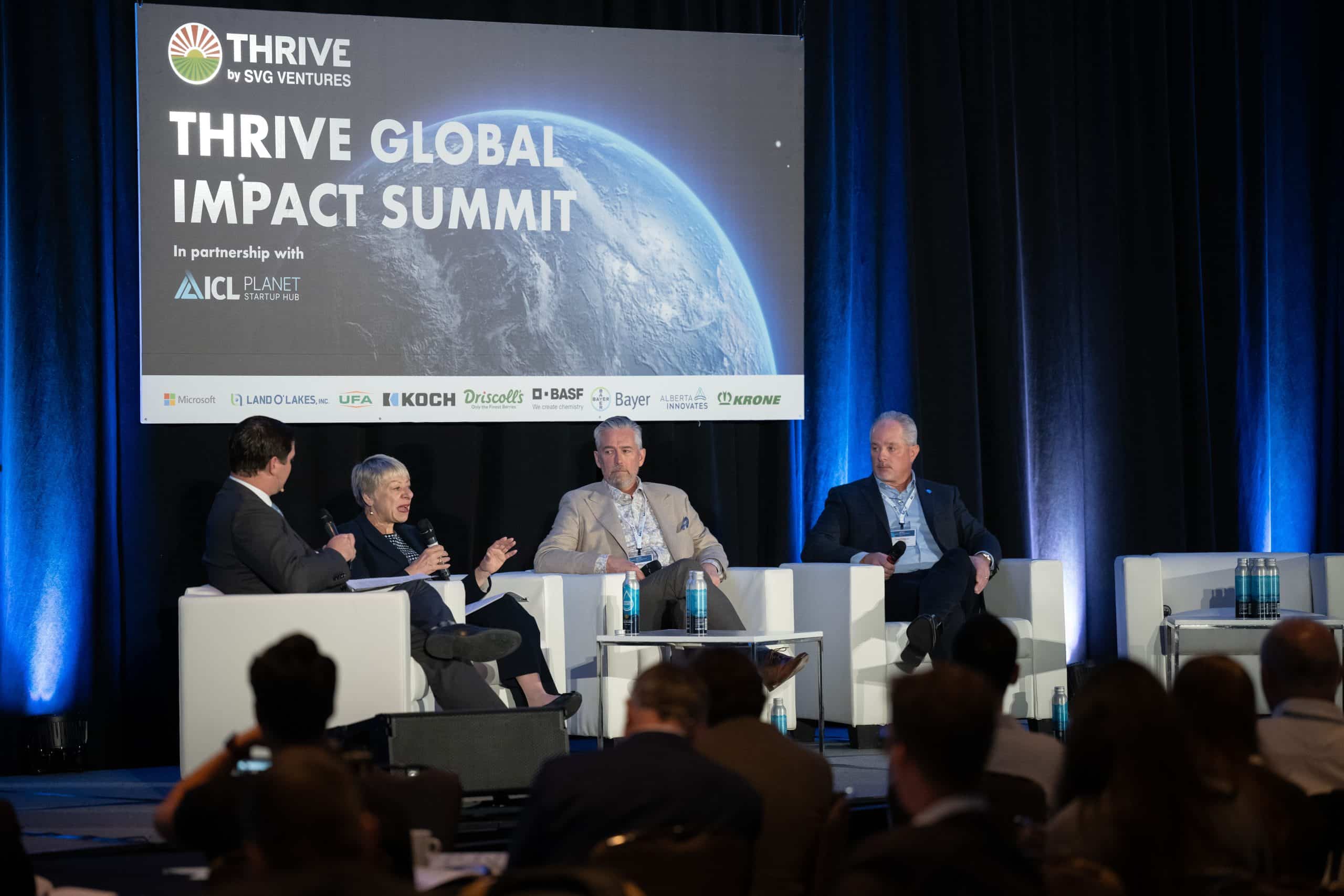 Panelists speaking beneath a THRIVE Global Impact Summit screen