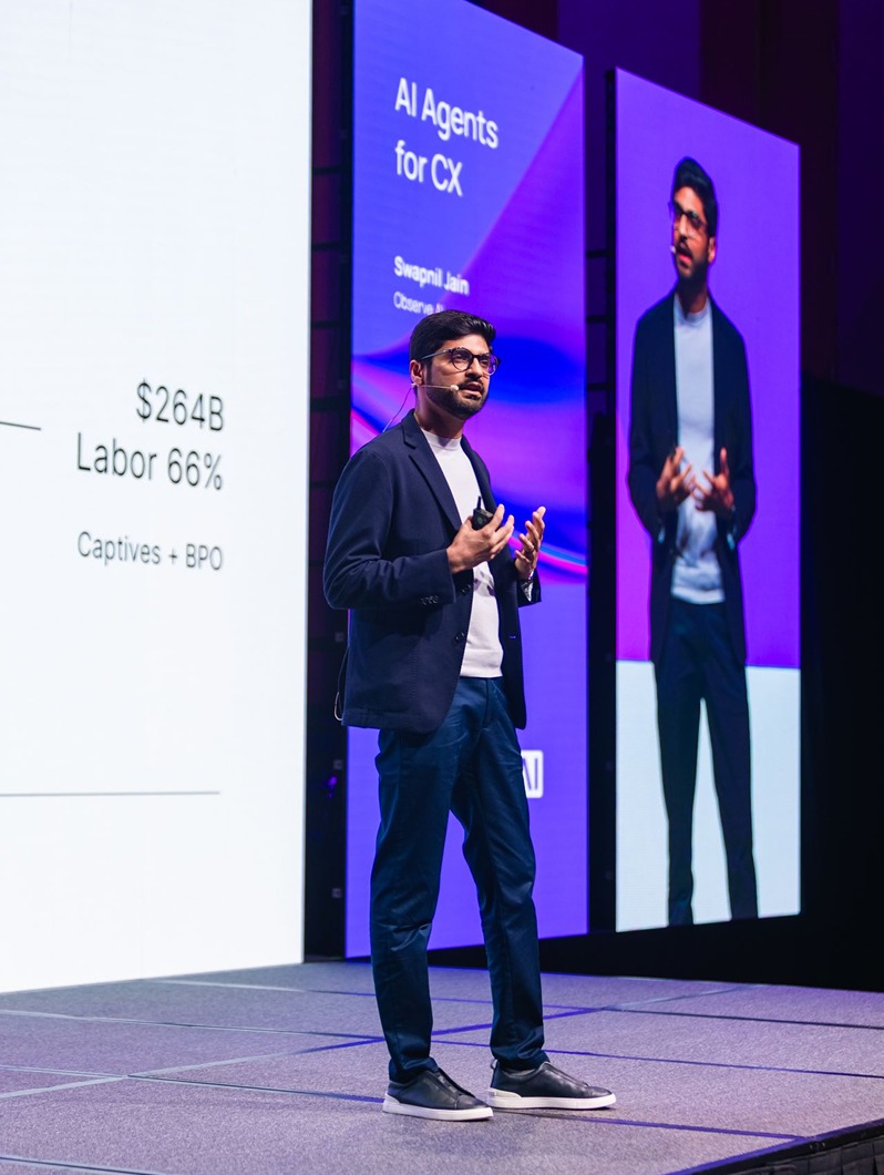 Swapnil Jain speaking onstage beside a presentation about AI agents for customer experience