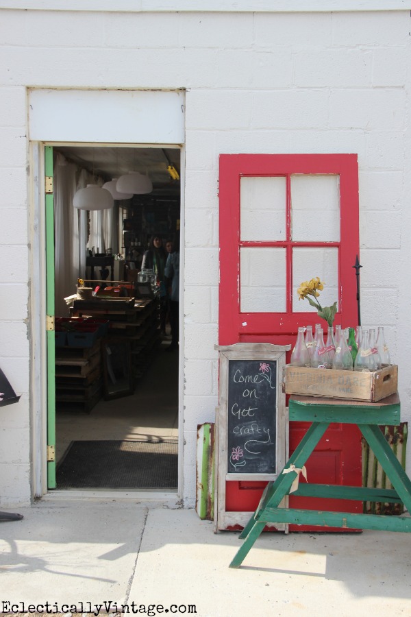 A green stool, red window frame and bottles beside Sweet Clover’s barn-era entrance