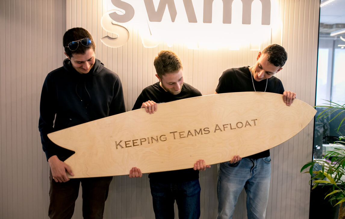 Swimm team members posing with a surfboard