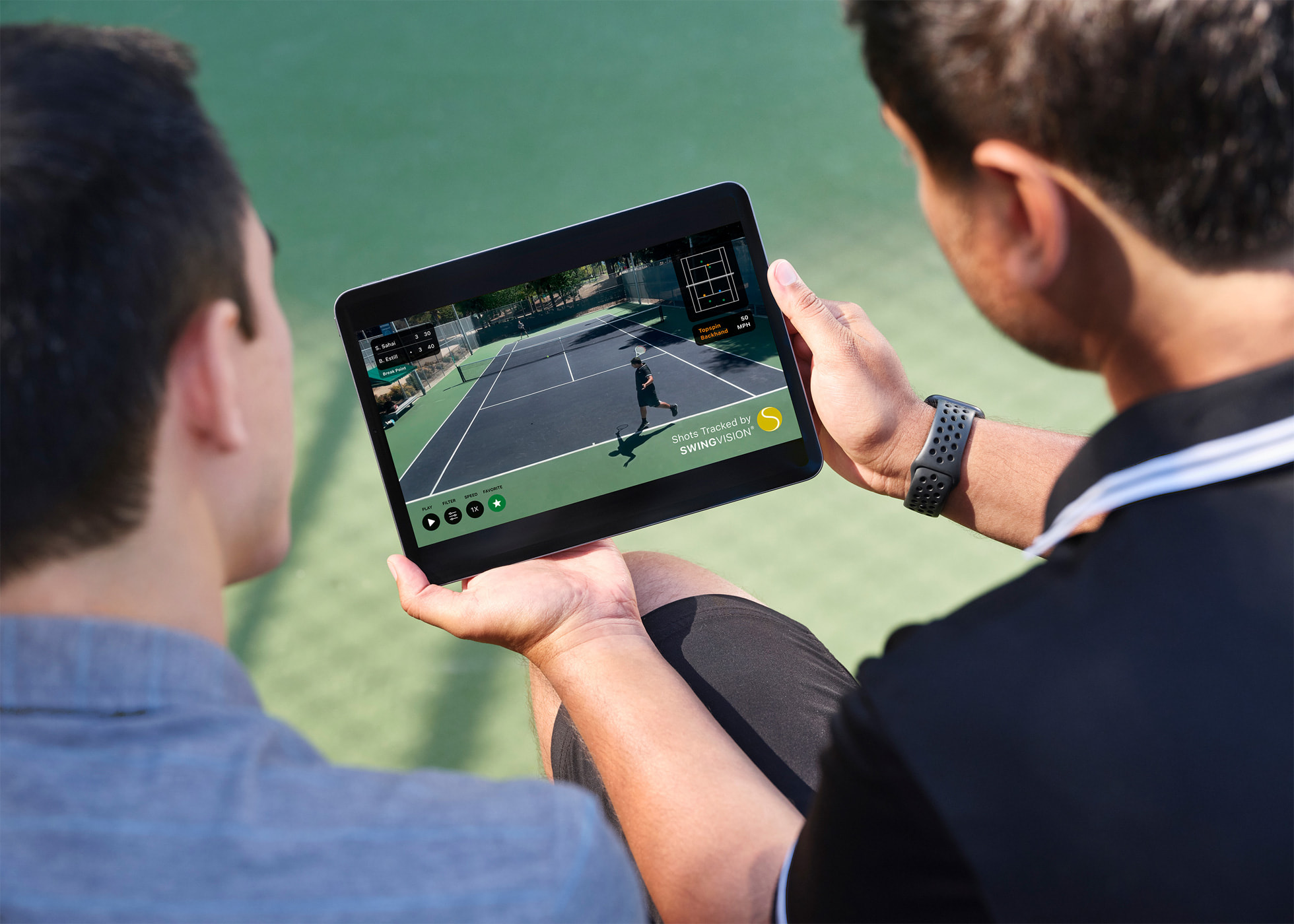 An iPhone mounted behind a tennis court recording two players