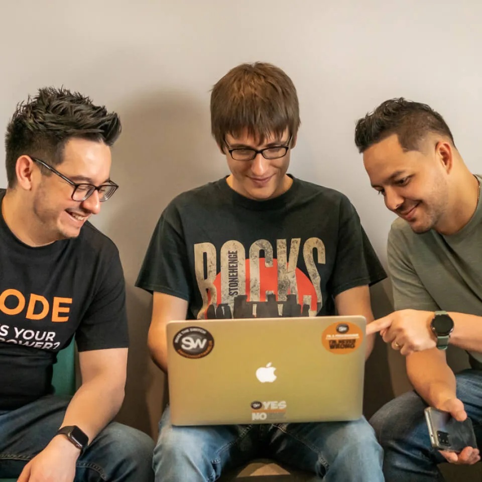 Three people gathered around a sticker-covered laptop in a photograph published by Switch Software.