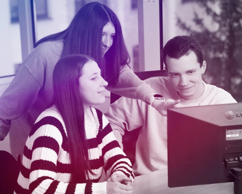 Three colleagues gathered around a monitor in Syberry’s company-published team photograph
