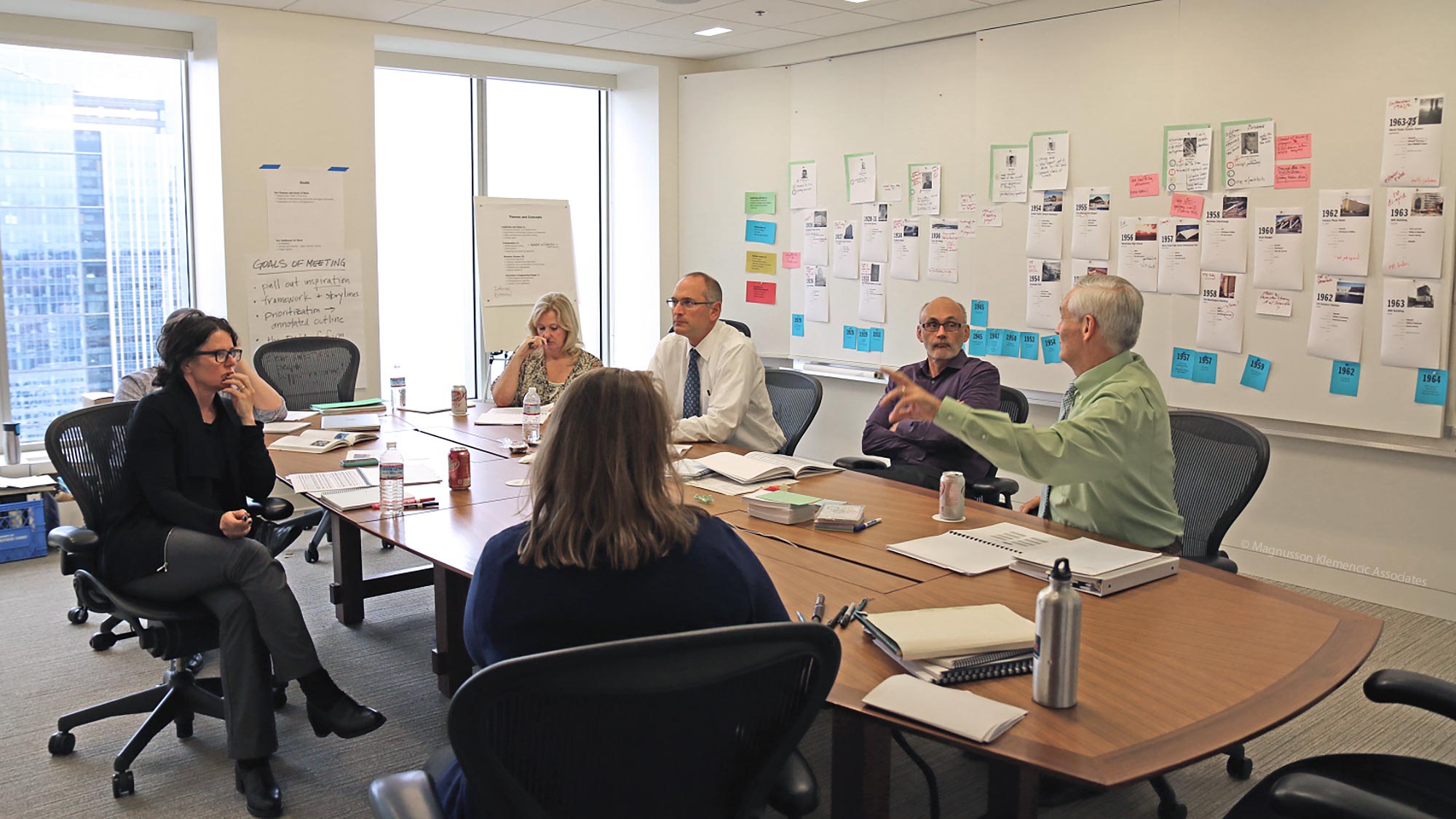 Photographs and project notes arranged around an MKA conference room during book planning