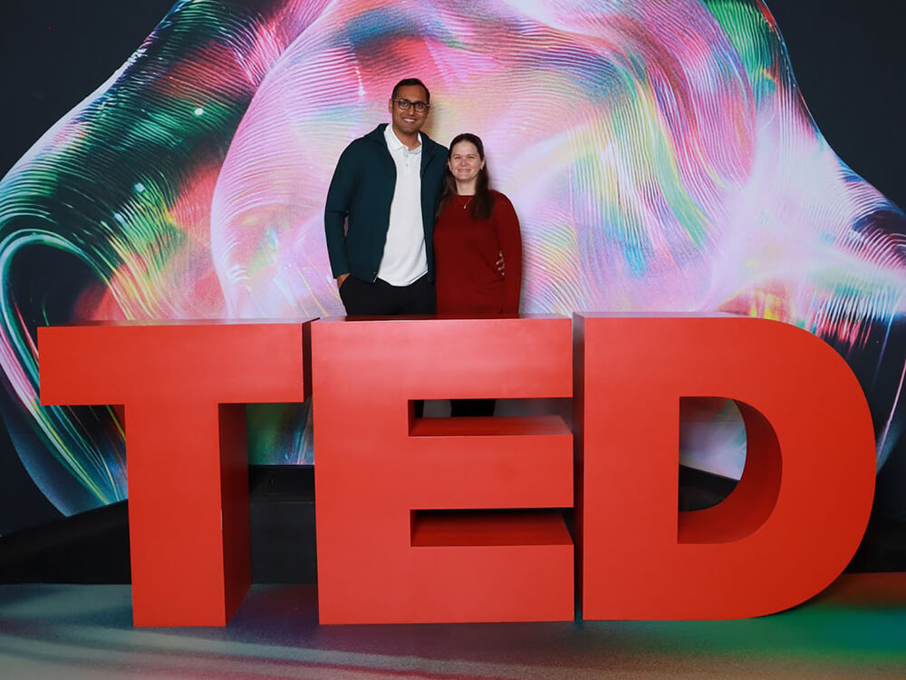 Syed and Amanda Balkhi standing behind large red TED letters in Vancouver