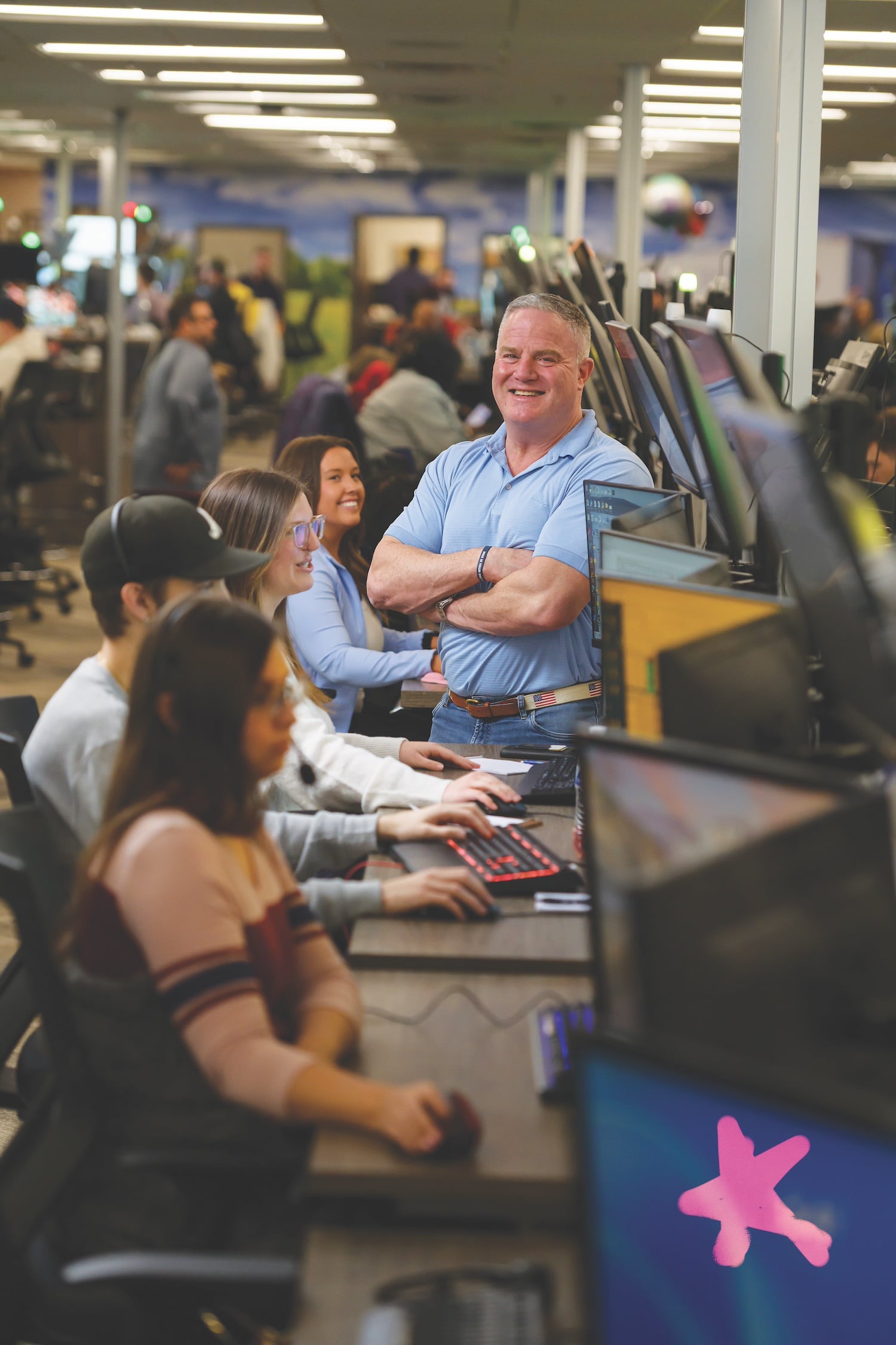 Steve Syfan standing among team members and computer workstations on the logistics operations floor