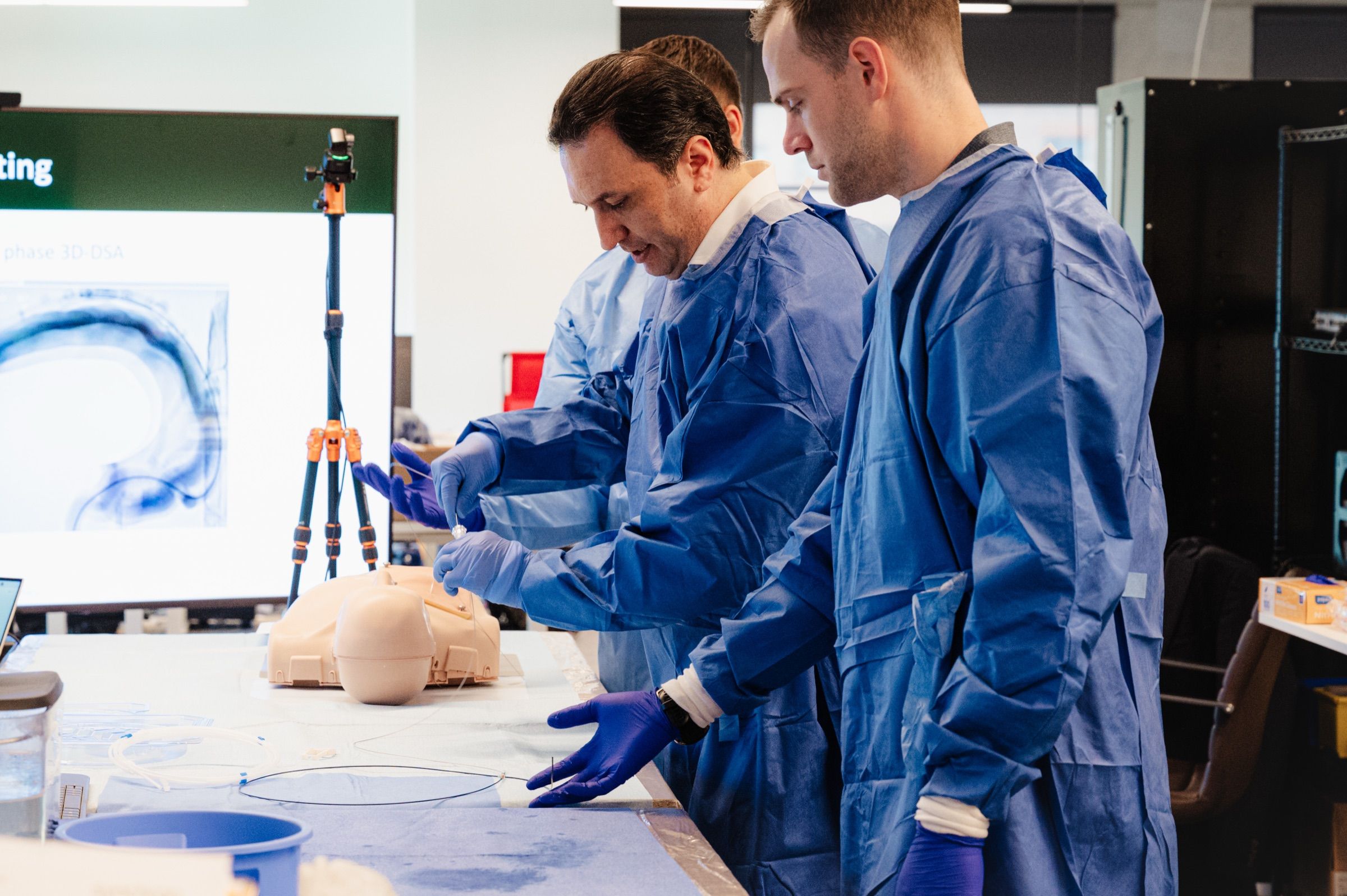 Synchron team rehearsing a catheter procedure with a head model in a laboratory