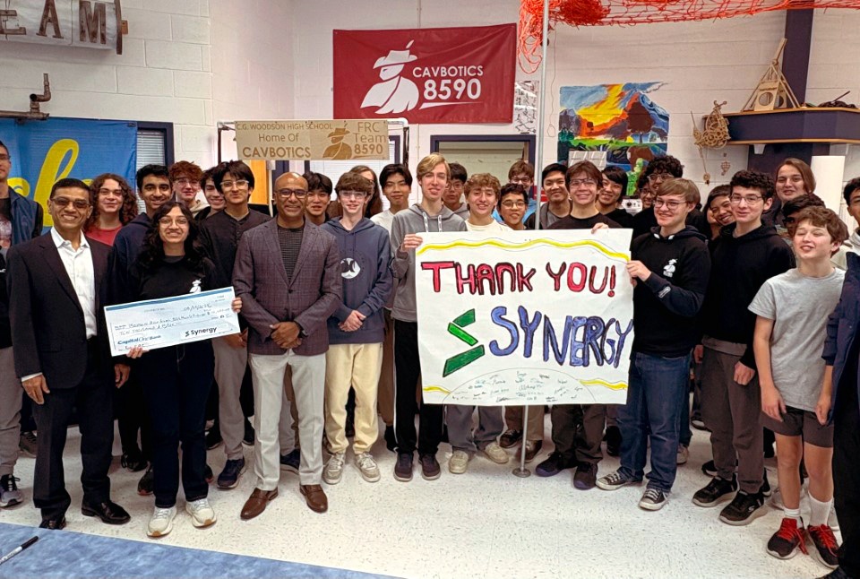 Synergy representatives presenting a sponsorship check to Woodson High School’s Cavbotics robotics team