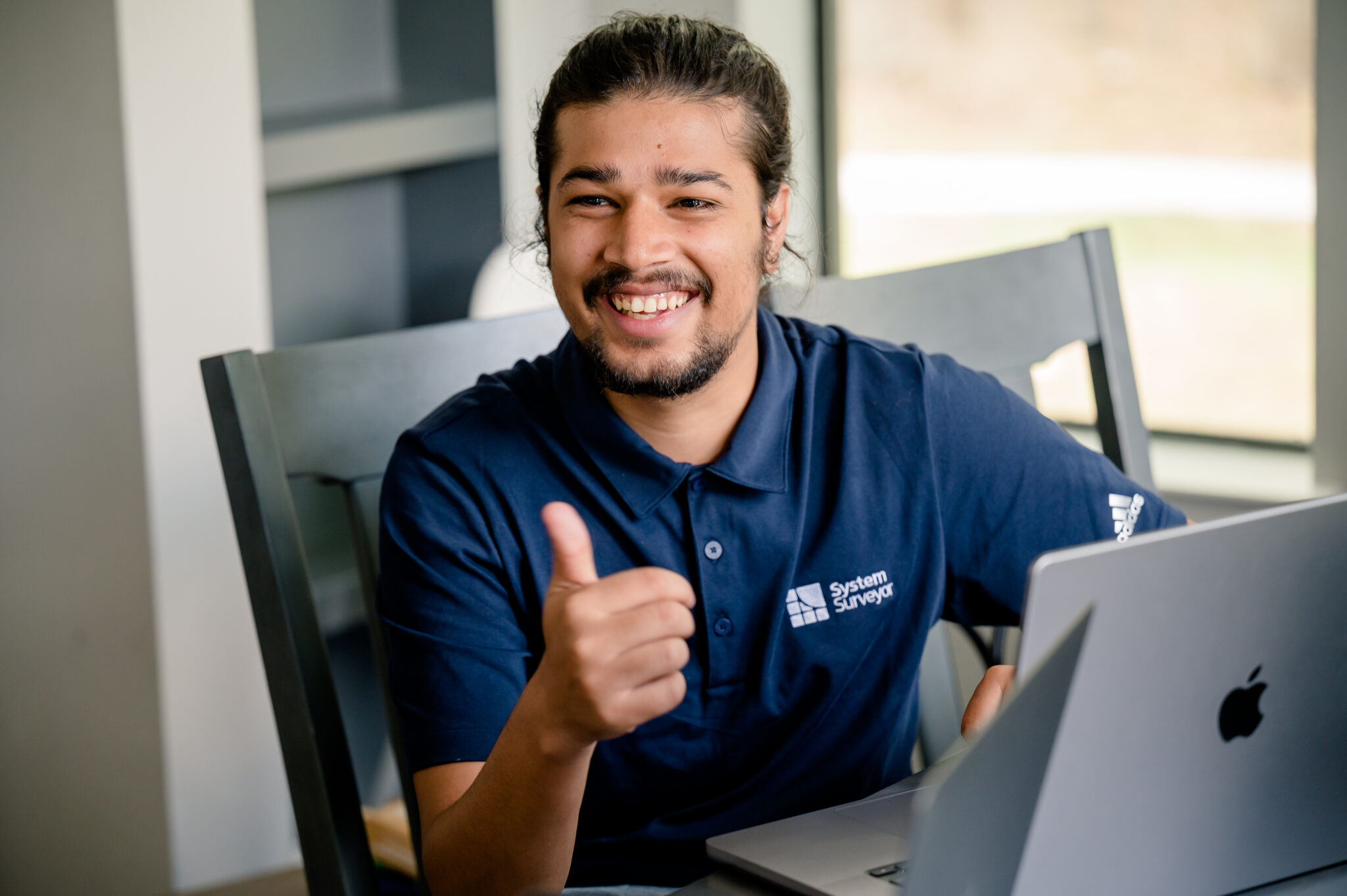 A System Surveyor team member smiling beside a laptop