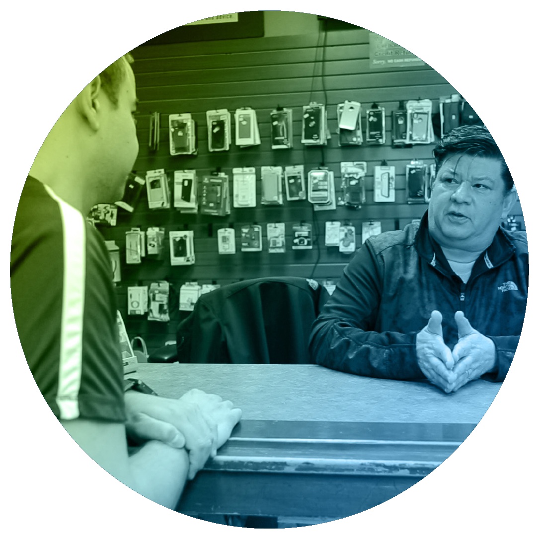 Two people talking across the counter of a wireless accessories store
