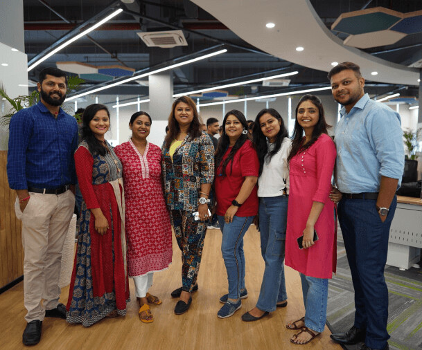 Eight Taazaa team members standing together in the company’s modern Noida office