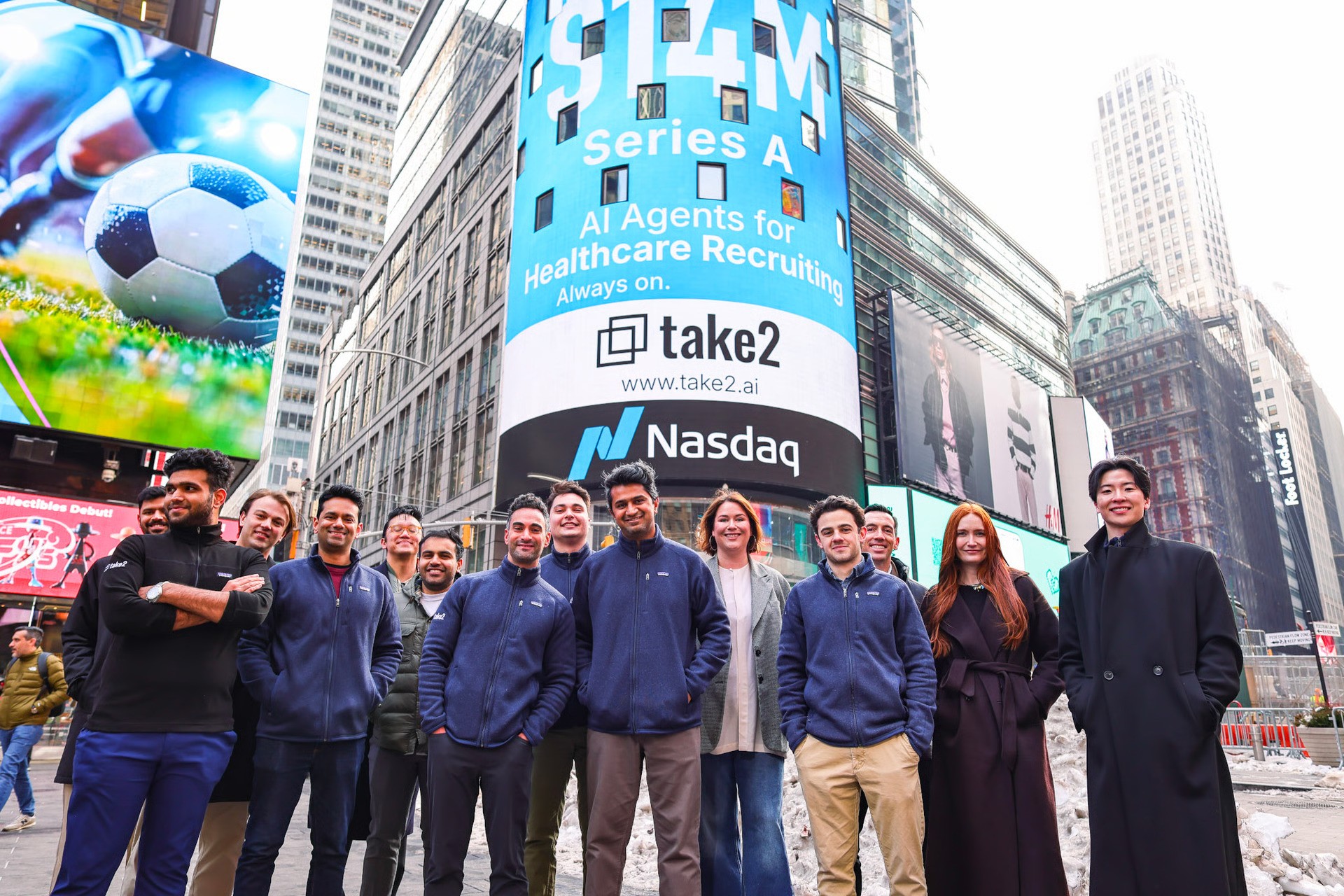 Take2 team standing in Times Square beneath a billboard announcing its $14 million Series A