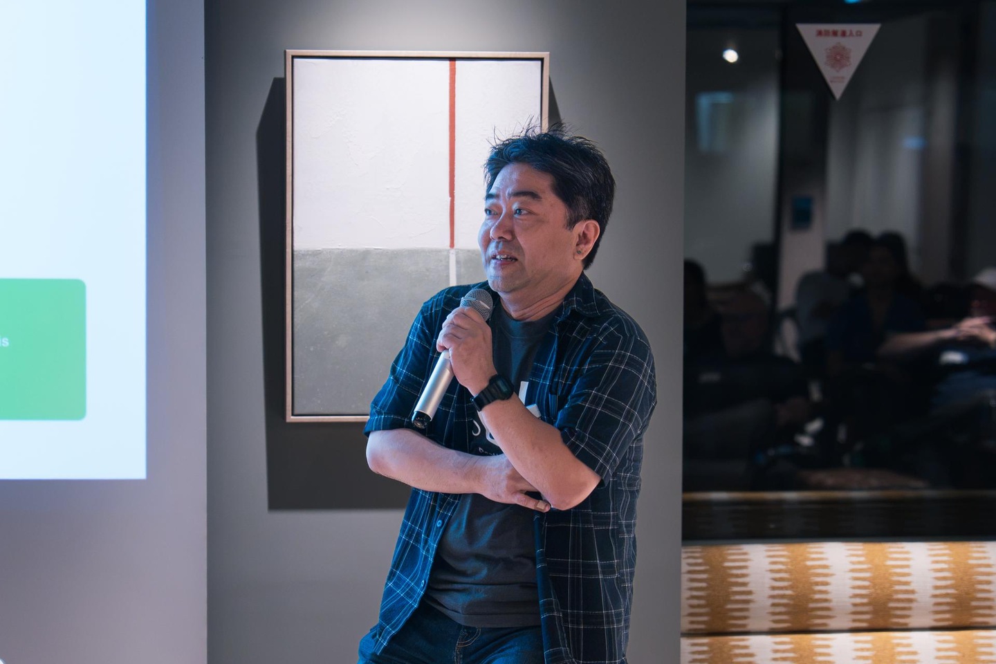 Taku Harada speaking into a handheld microphone at the September 2026 Kokusai Startup Meetup.