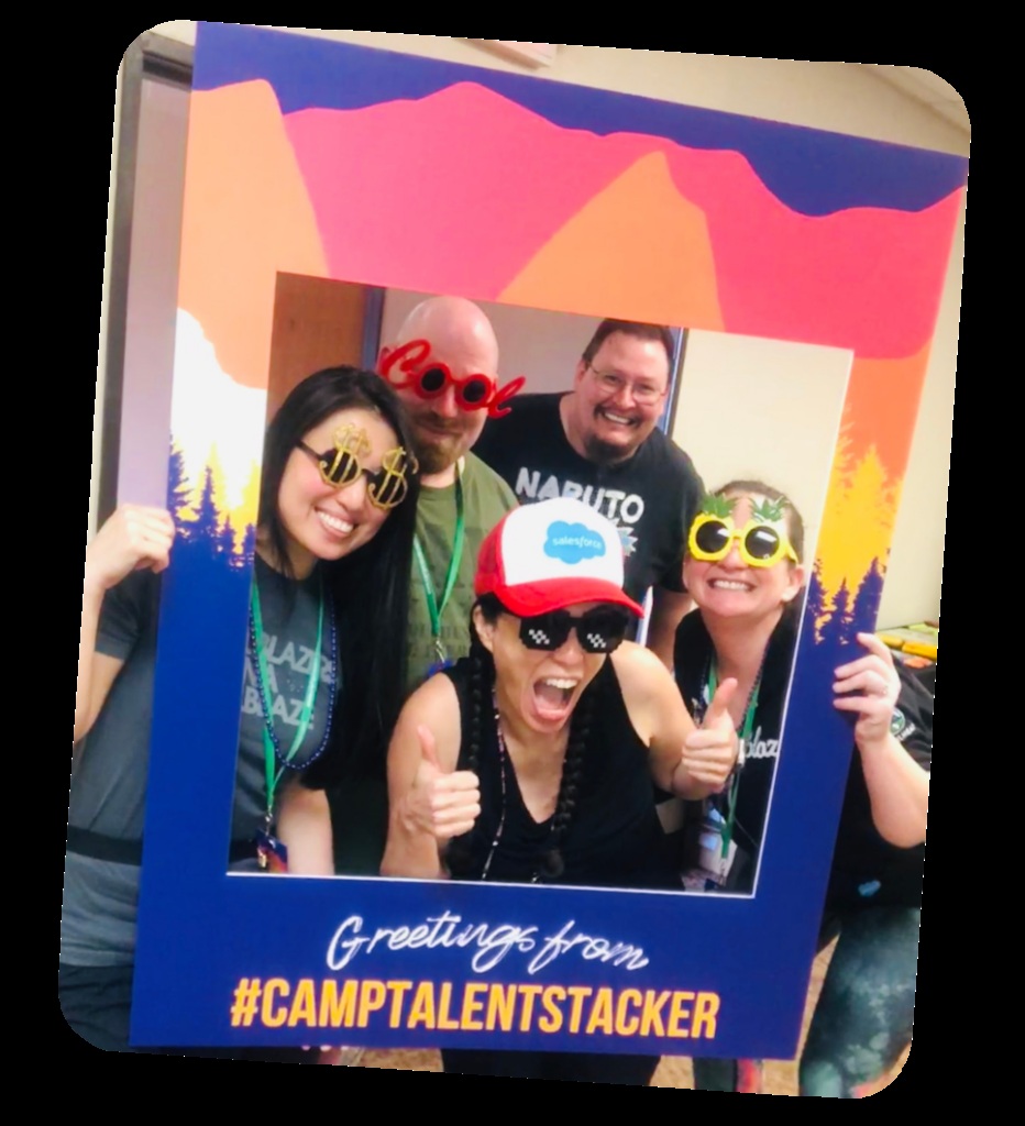 Five people wearing playful sunglasses pose inside a Camp Talent Stacker photo-booth frame