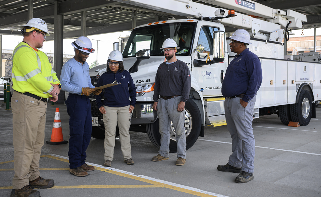 Tamla Olivier in a hard hat alongside four BGE field employees beside a bucket truck