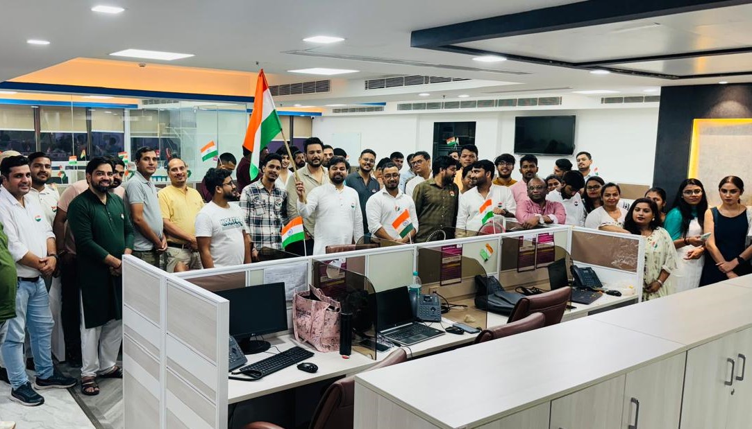 Tanisha Systems colleagues gathered between office desks, holding Indian flags