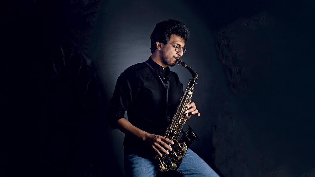 Tanmaya Jain seated and playing a saxophone