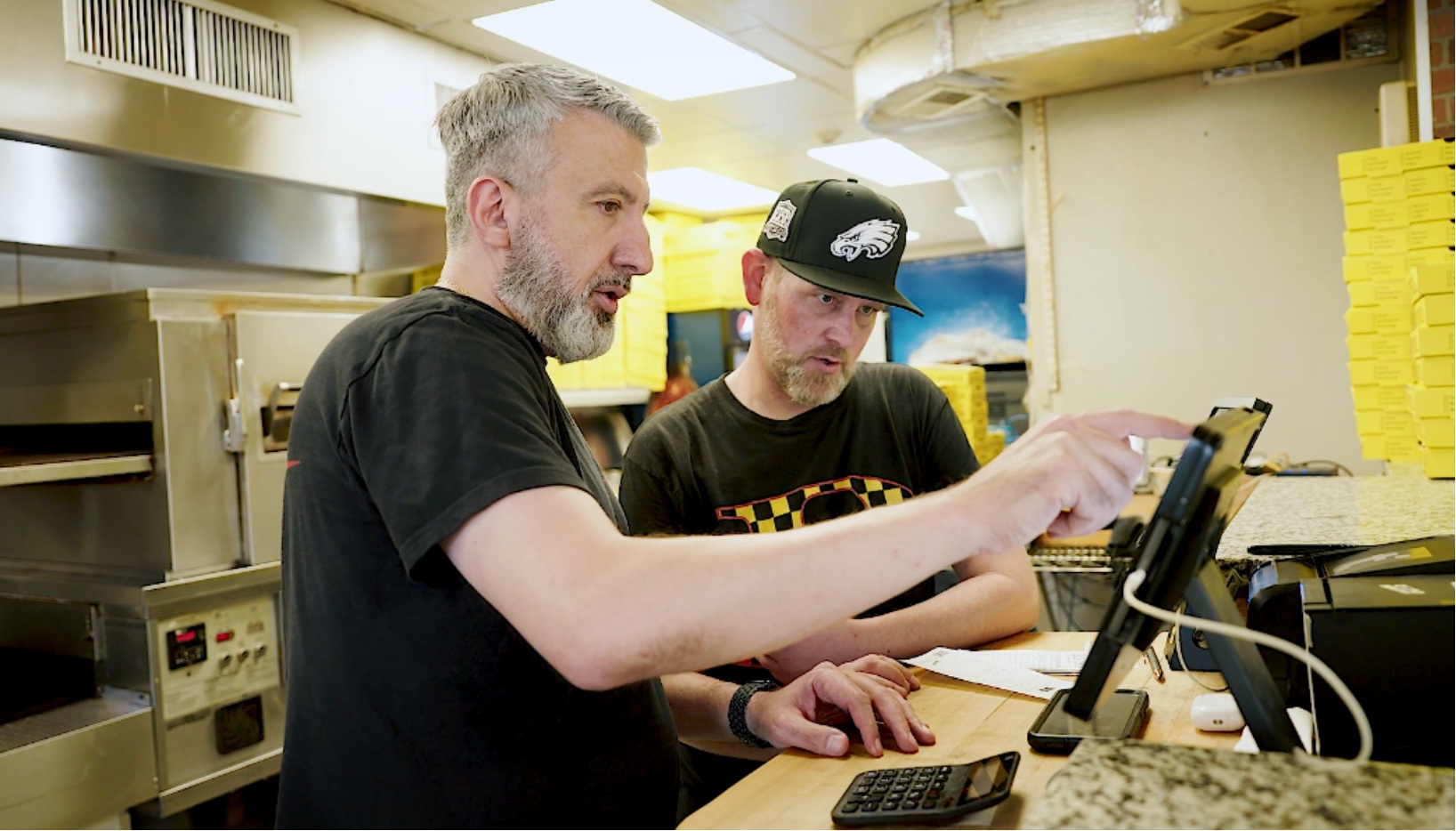 Two Pete’s Pizza operators looking at a tablet on the counter