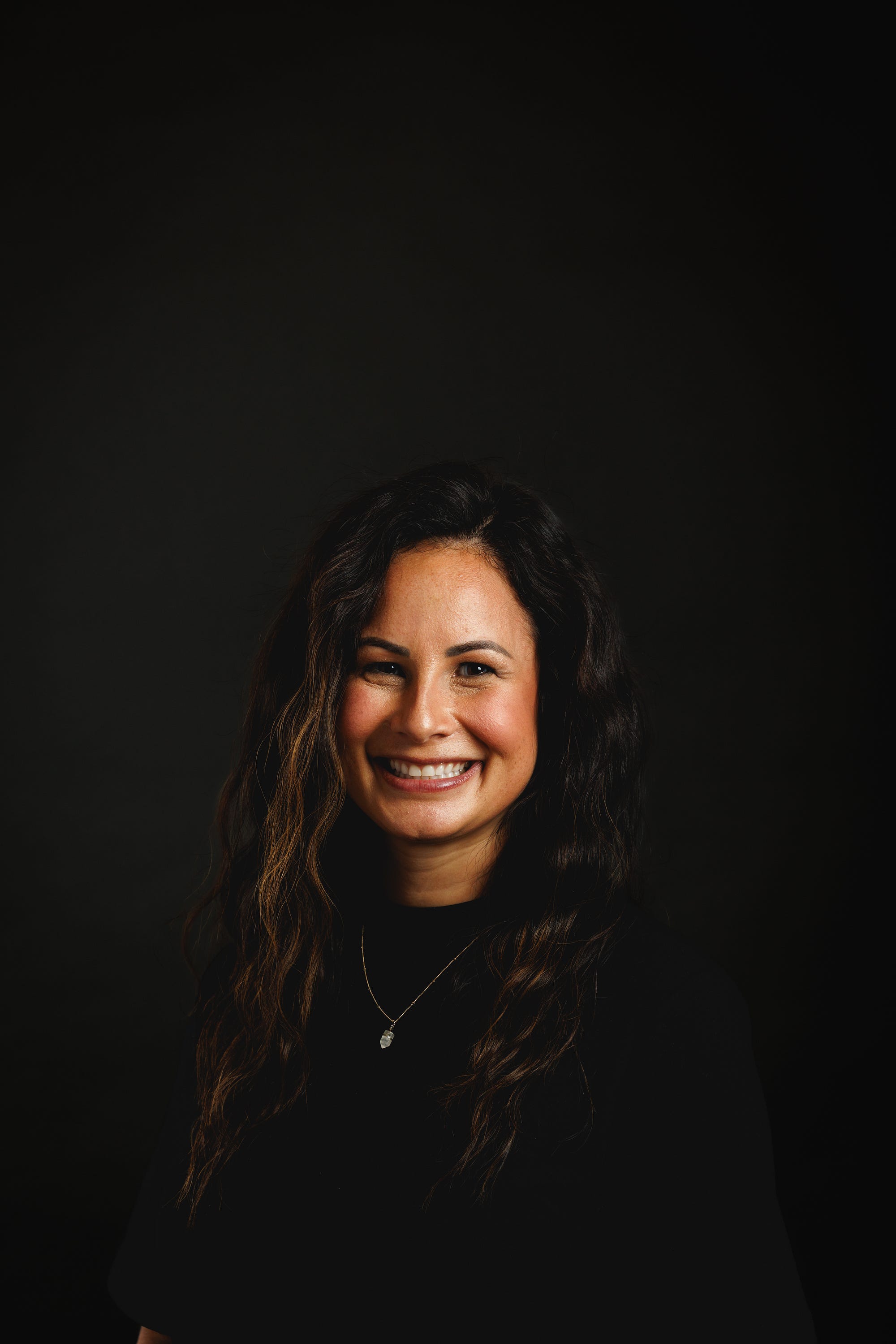 Tasha Reasor smiling against a dark studio background