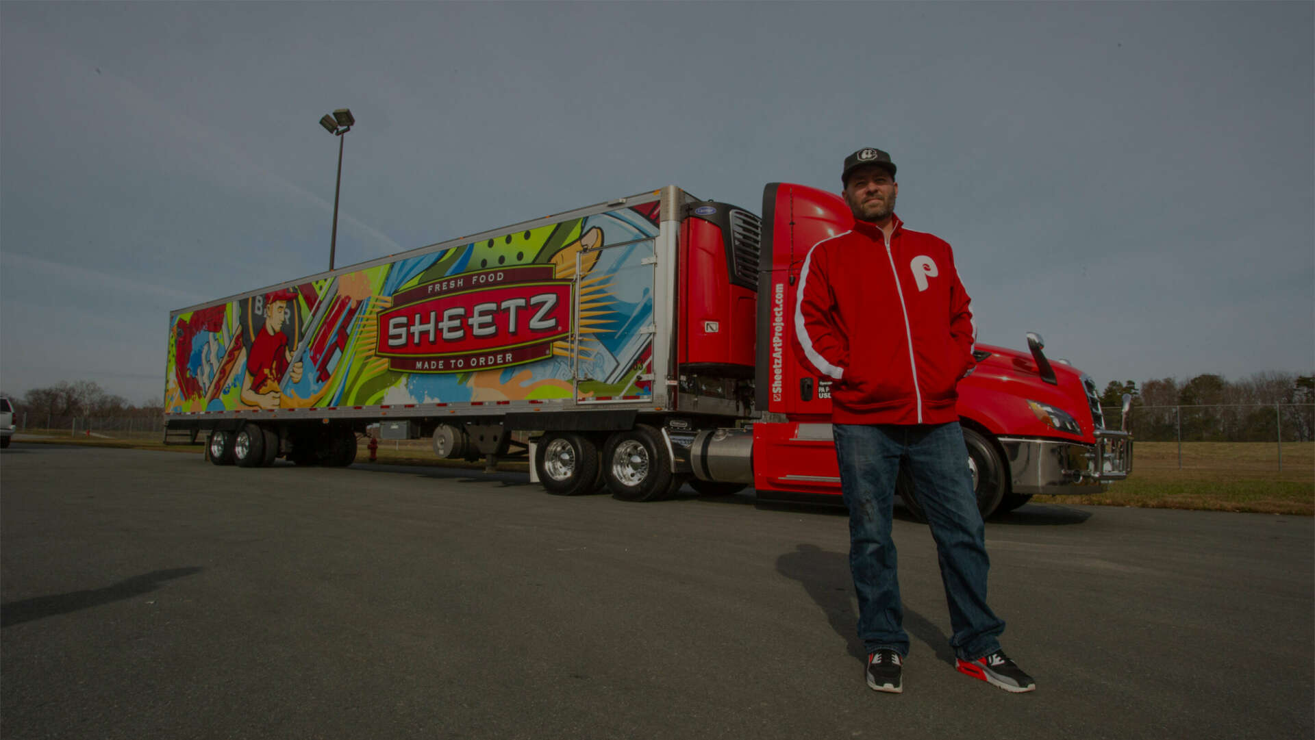 A Sheetz fleet-art truck with colorful original artwork beside a man in a red jacket