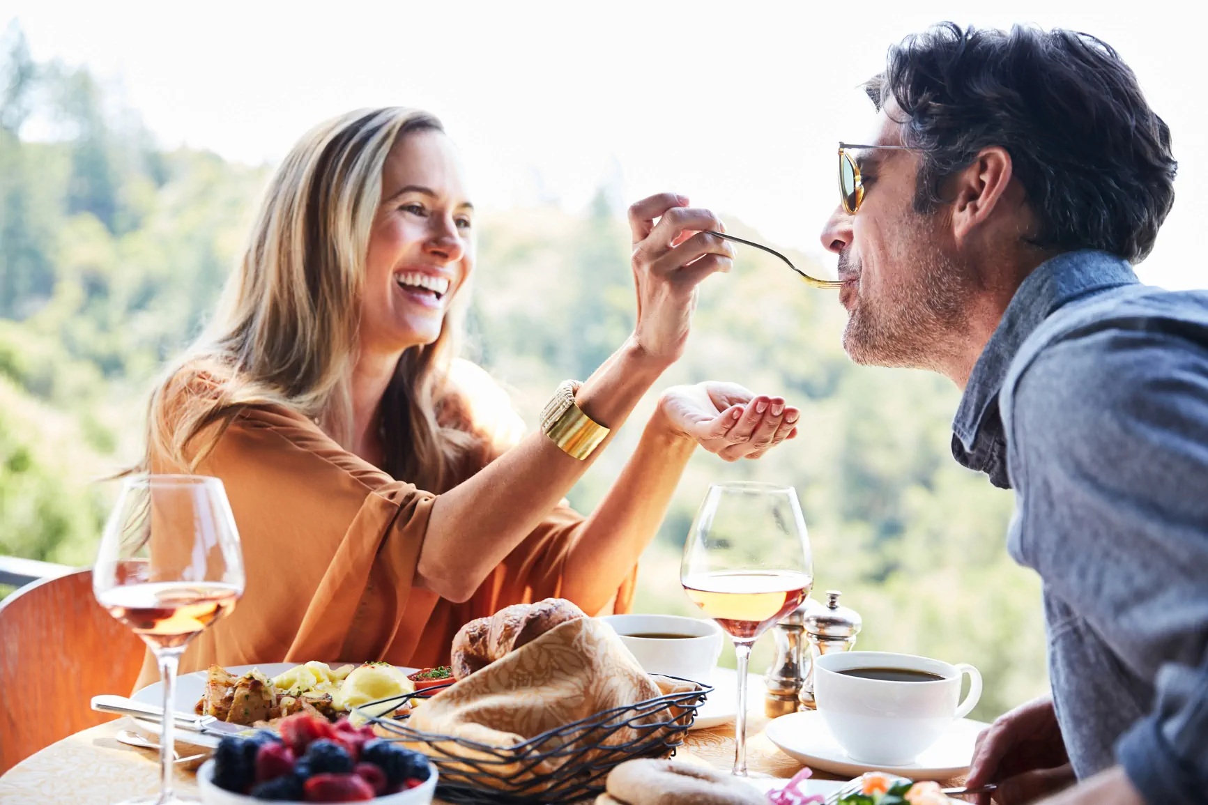 A smiling couple sharing a spoonful of food at a restaurant table