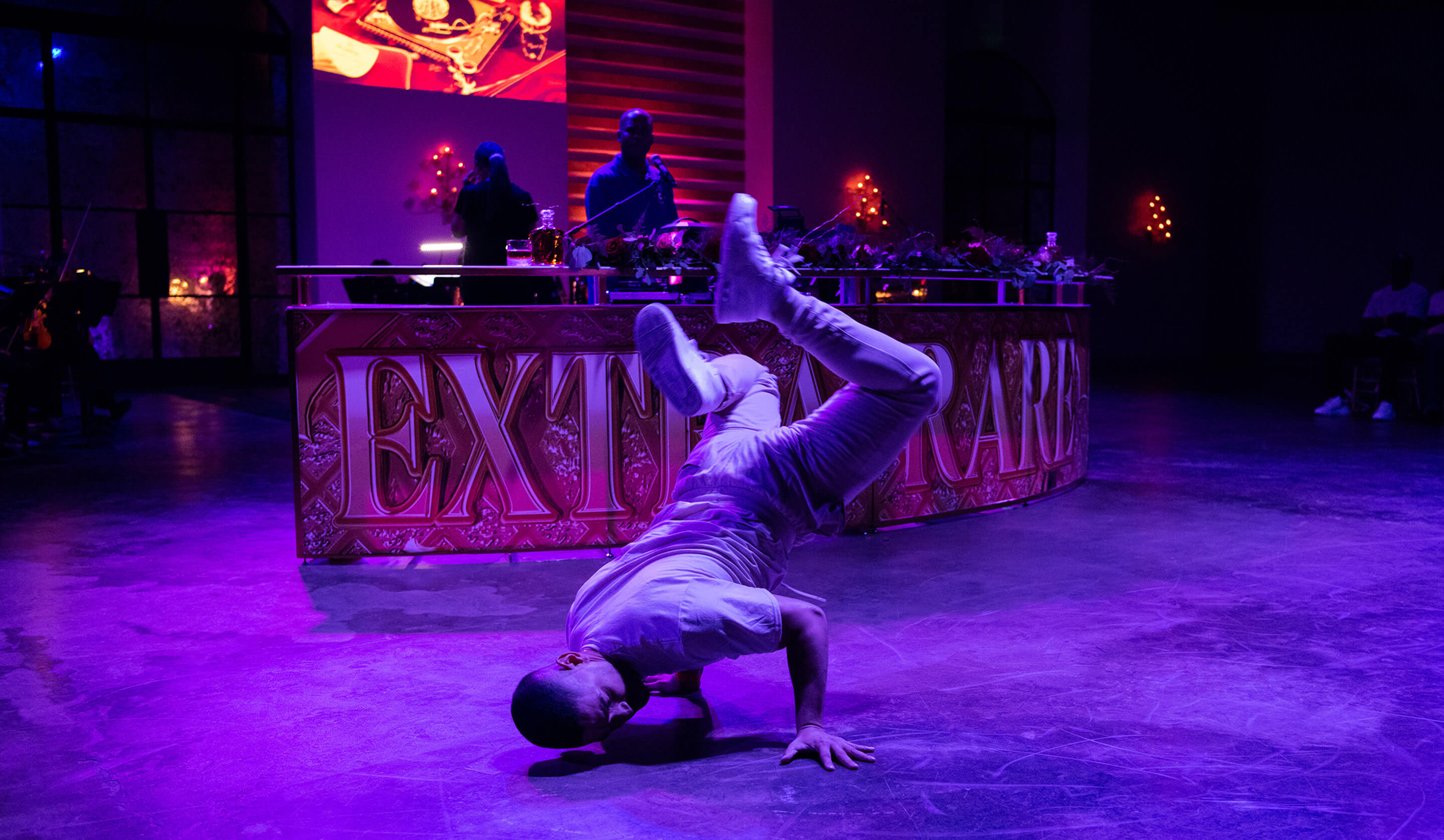A breakdancer performs in front of an illuminated bar in an event image from Taylor's portfolio
