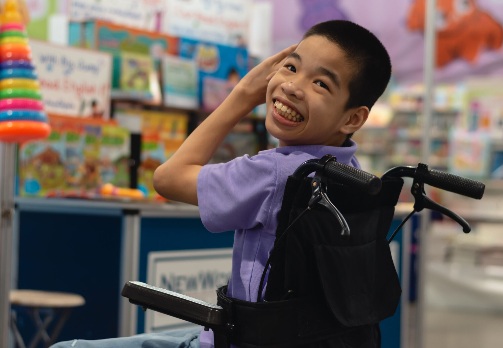 A smiling student using a wheelchair in a colorful classroom