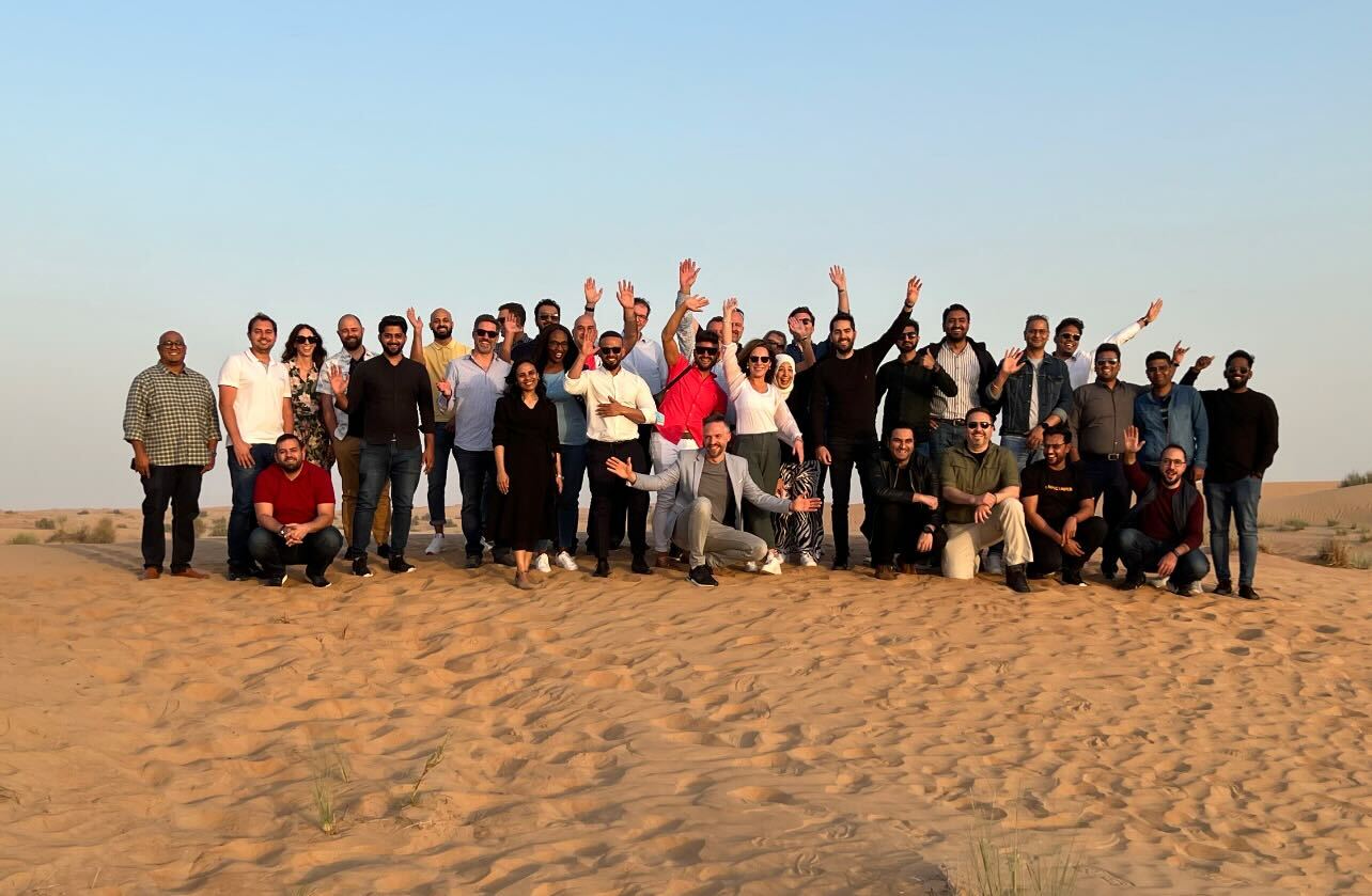 A group of Tealium team members posing outdoors on sand dunes
