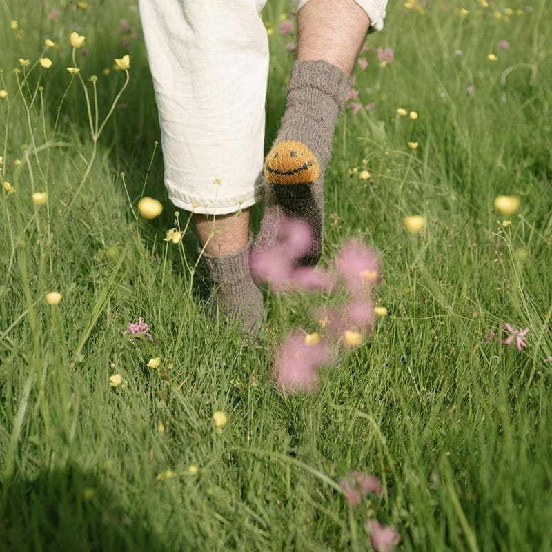 Person walking through a meadow wearing socks decorated with a smiley face, from Teamtailor's onboarding campaign