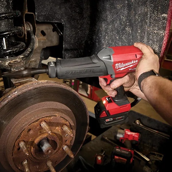 A technician using a Milwaukee M18 FUEL STRIKER hammer chisel beside a vehicle brake assembly