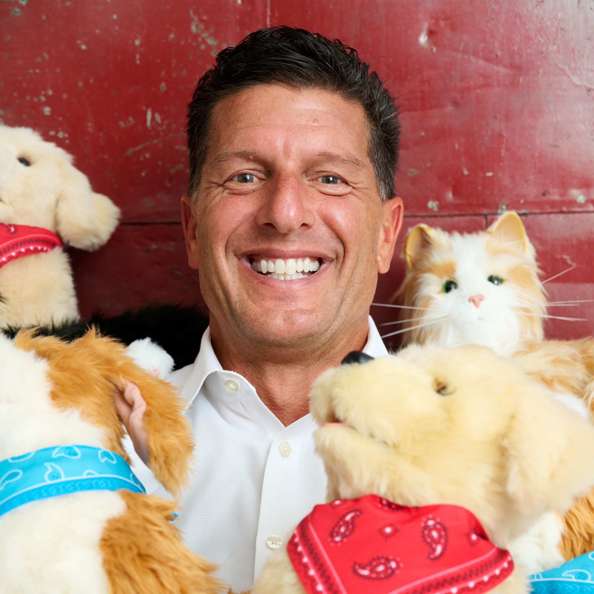 Ted Fischer smiling with several Joy for All robotic companion pets