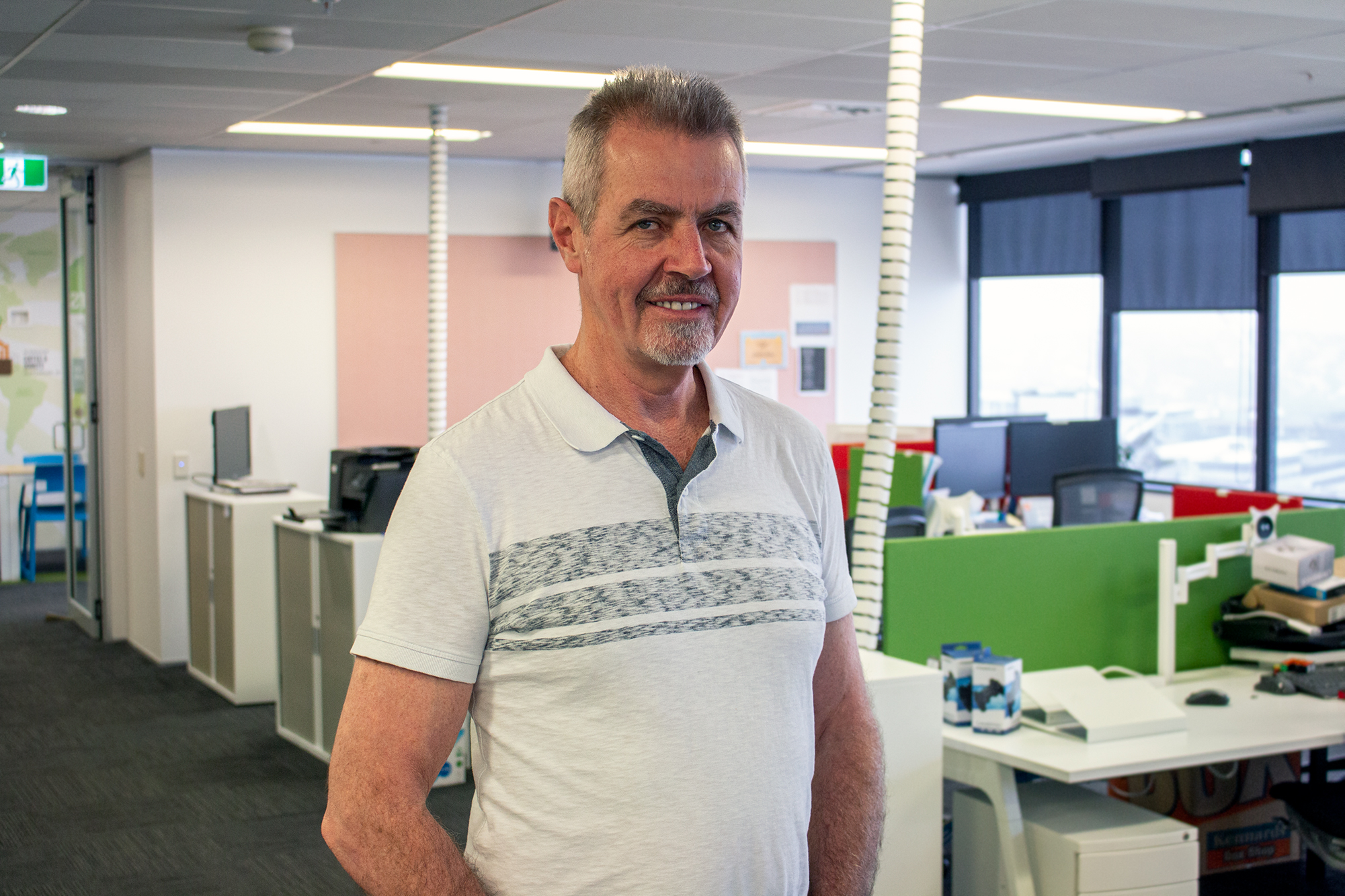 Ted Jordan standing among desks in an Actionstep office