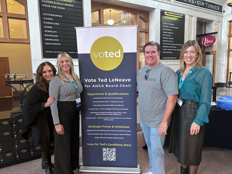Ted LeNeave and three industry colleagues standing beside a Vote Ted LeNeave for AHCA Board Chair sign at a conference reception