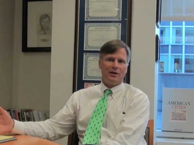 Ted Virtue speaking in his office, wearing a white shirt and green tie