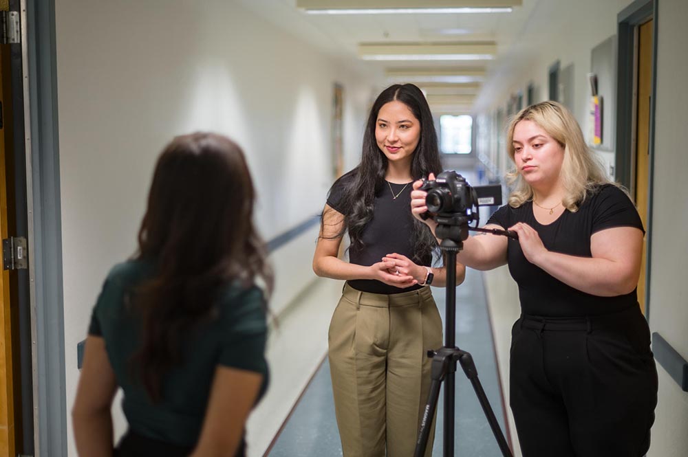 Chico State students frame a camera shot while filming another student in a hallway