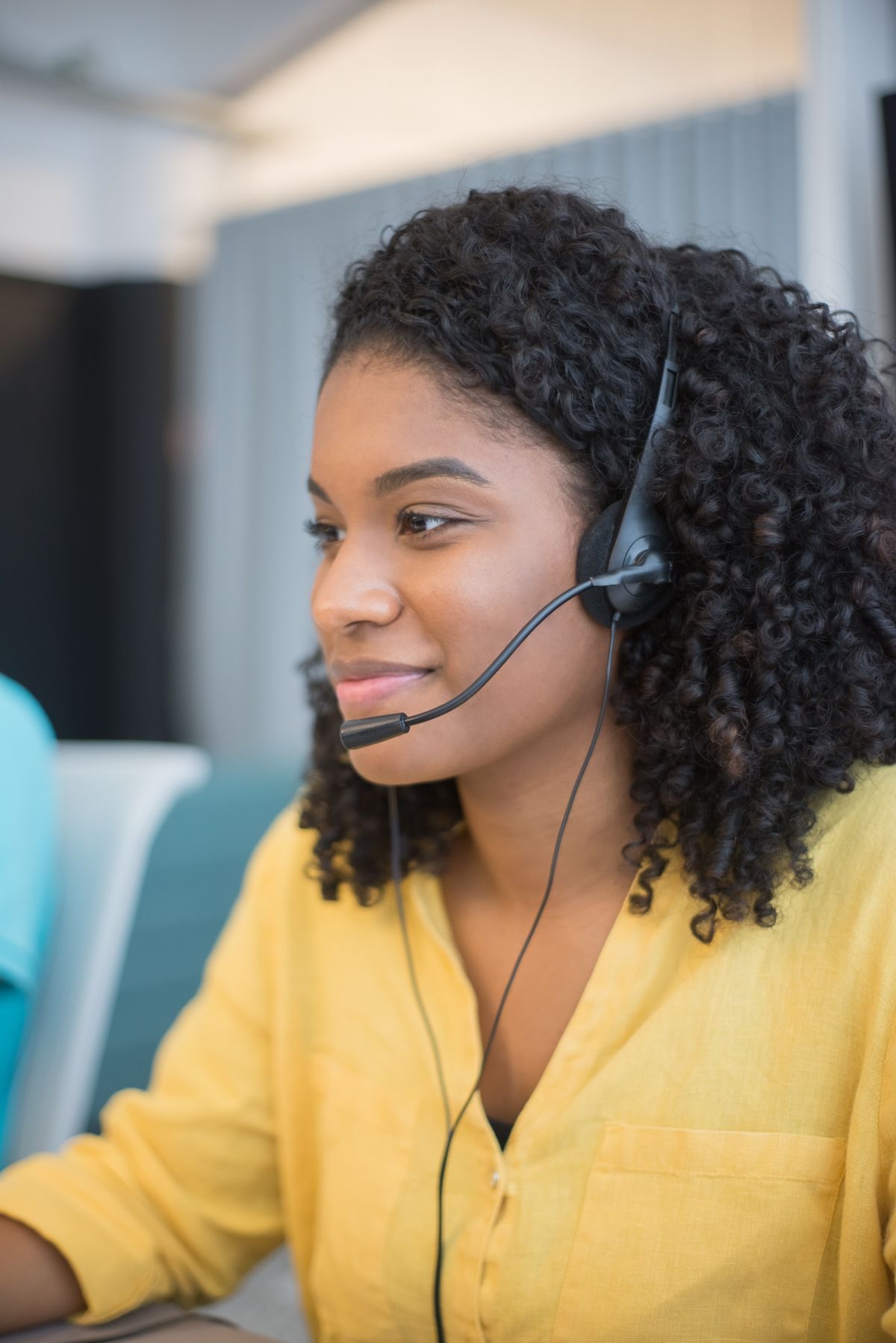 A headset-wearing customer support worker at a desk