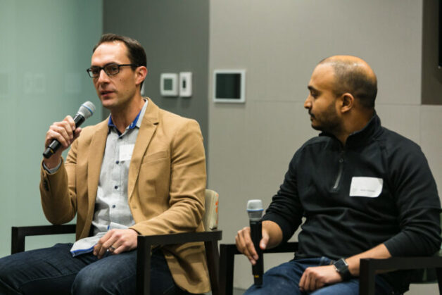 Two seated participants holding microphones at a fintech discussion