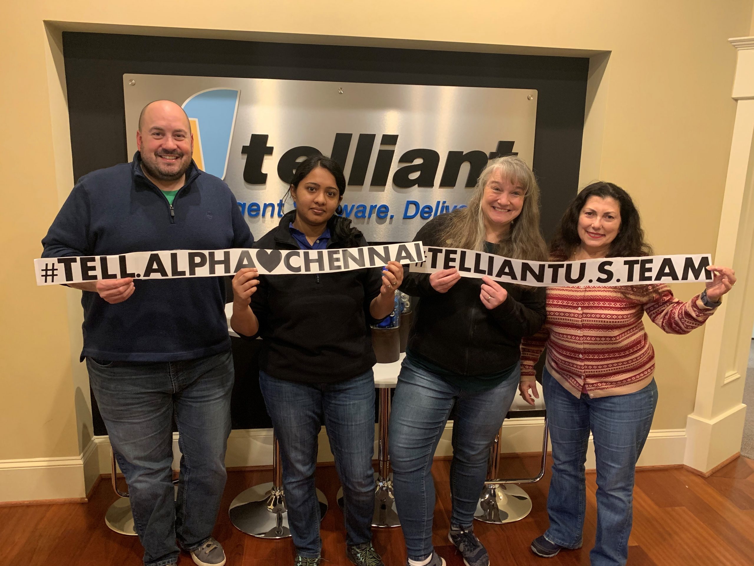 Four Telliant team members holding signs linking Alpharetta and Chennai
