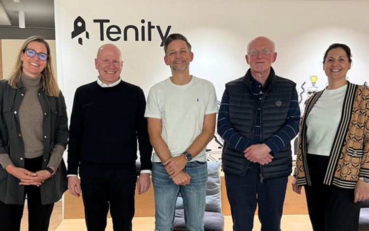 Five representatives stand together at Tenity’s office beneath its rocket logo.