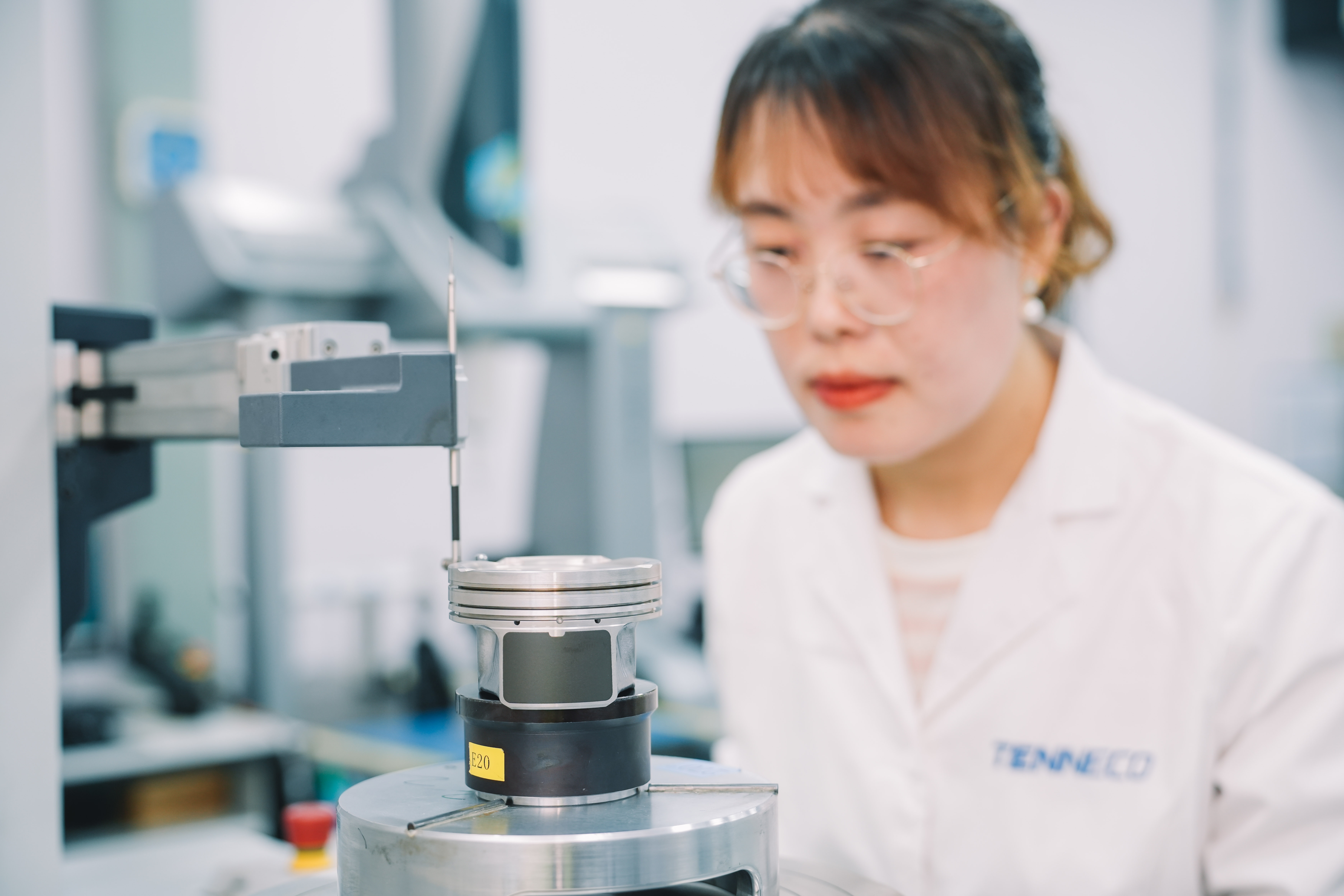 Tenneco laboratory worker examining a piston on precision measuring equipment