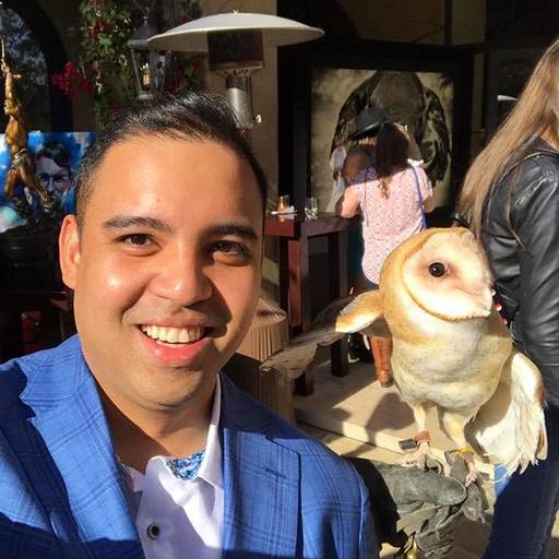 Teo Vanyo smiling beside an owl perched on a gloved hand