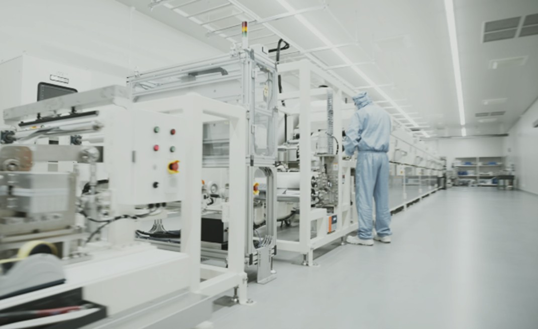 Worker in protective clothing beside battery manufacturing equipment at TeraWatt's Japanese production facility