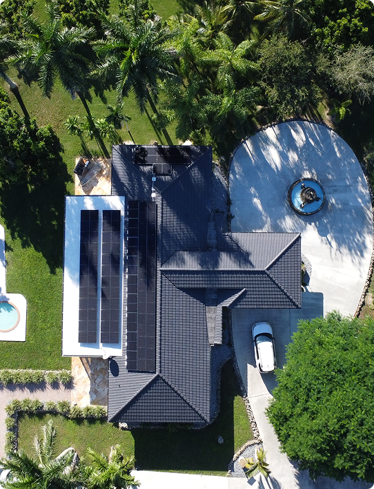 Overhead drone view of a large home with pool, driveway and rooftop solar array